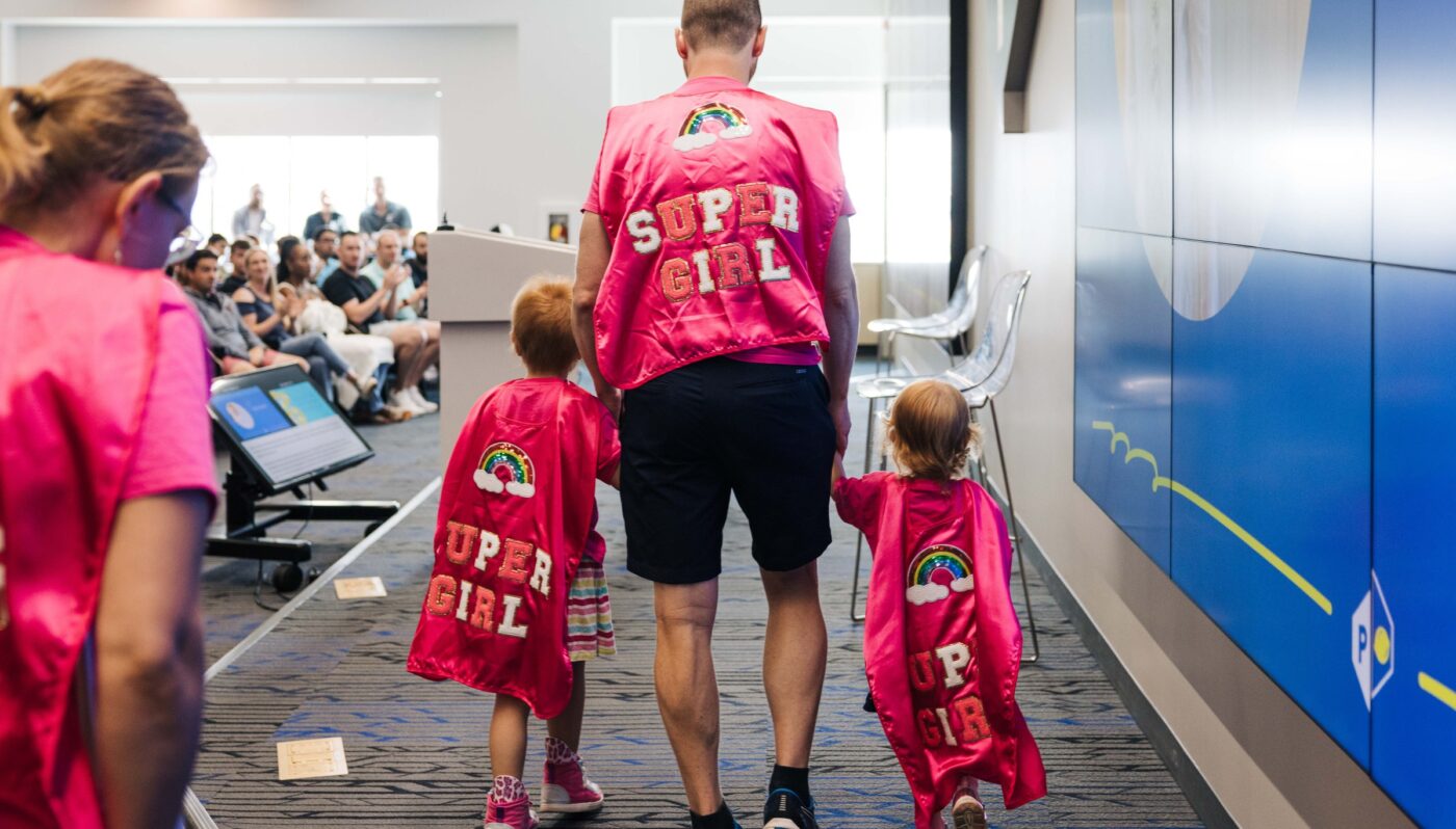 Father holds hands of two children, welcoming them to POWER's kickoff event or their Summer of Alex's initiative that raises money for childhood cancer.