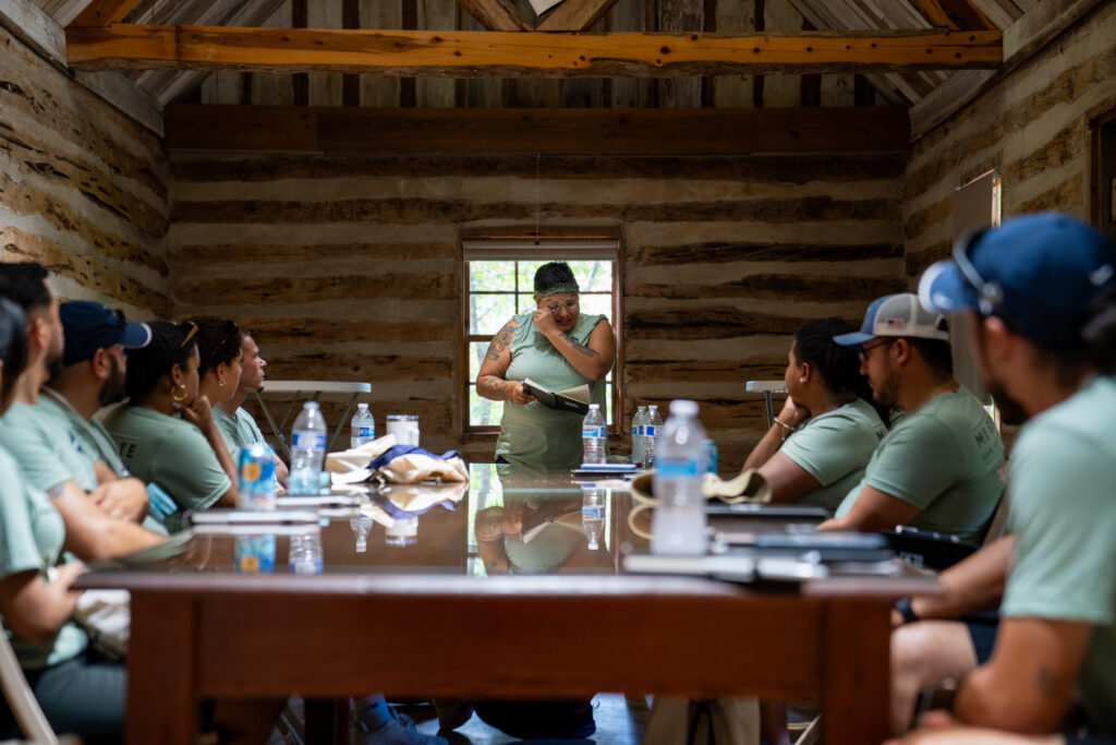 Employees sit around a table and listen to a teammate share an emotional journal entry during breakout sessions.