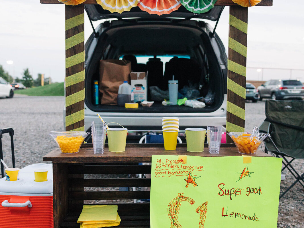 A lemonade stand is set up out of the trunk of a car during one of POWER's Kickball events to raise money for childhood cancer.