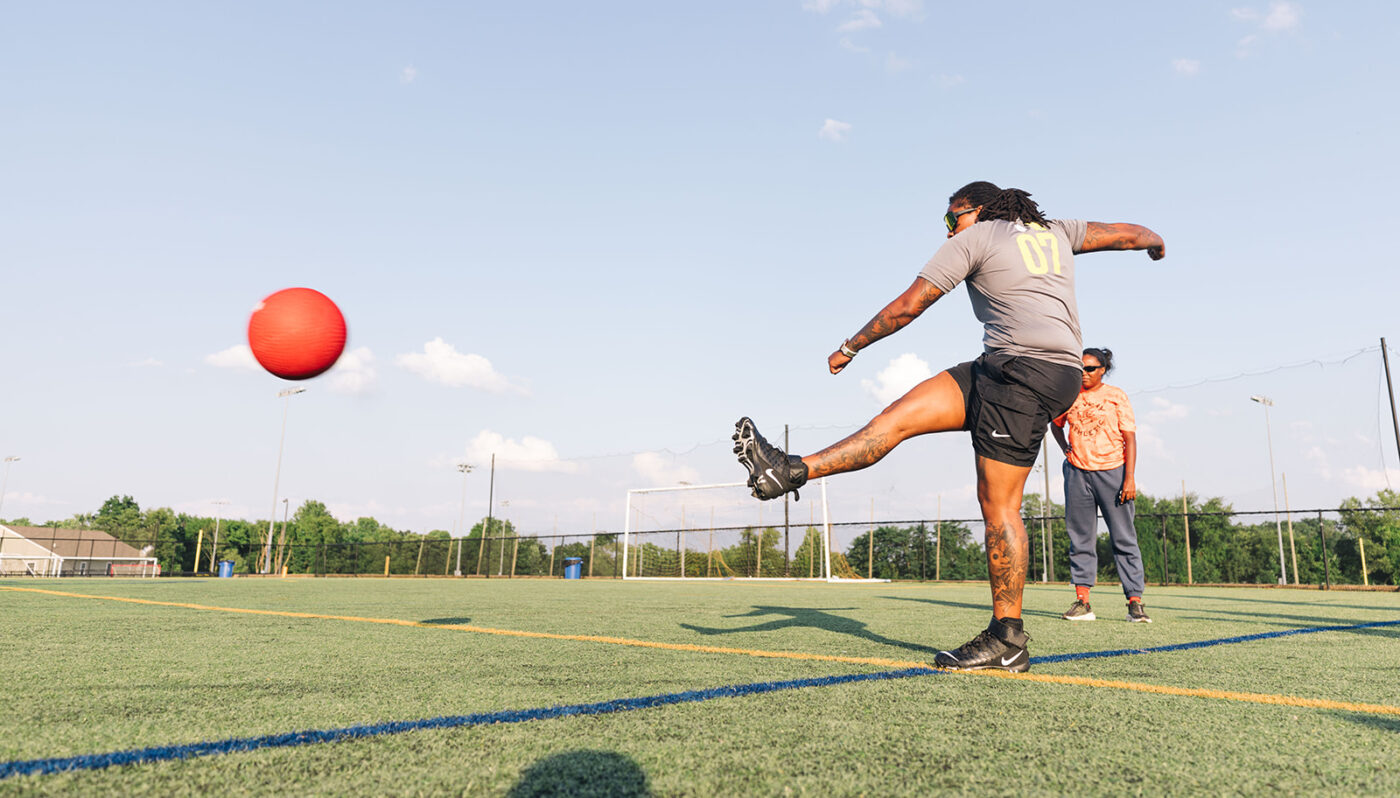 Employee kicks a ball during POWER's Kickball game to raise money for childhood cancer research.