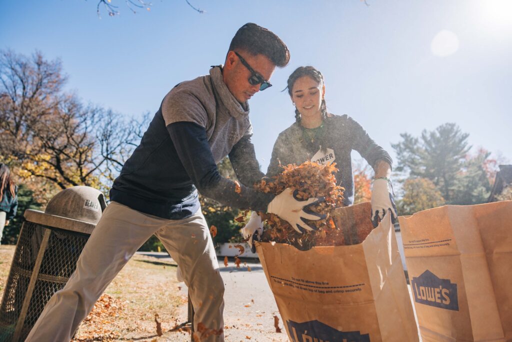 POWER employees help one another bag leaves during volunteer project.